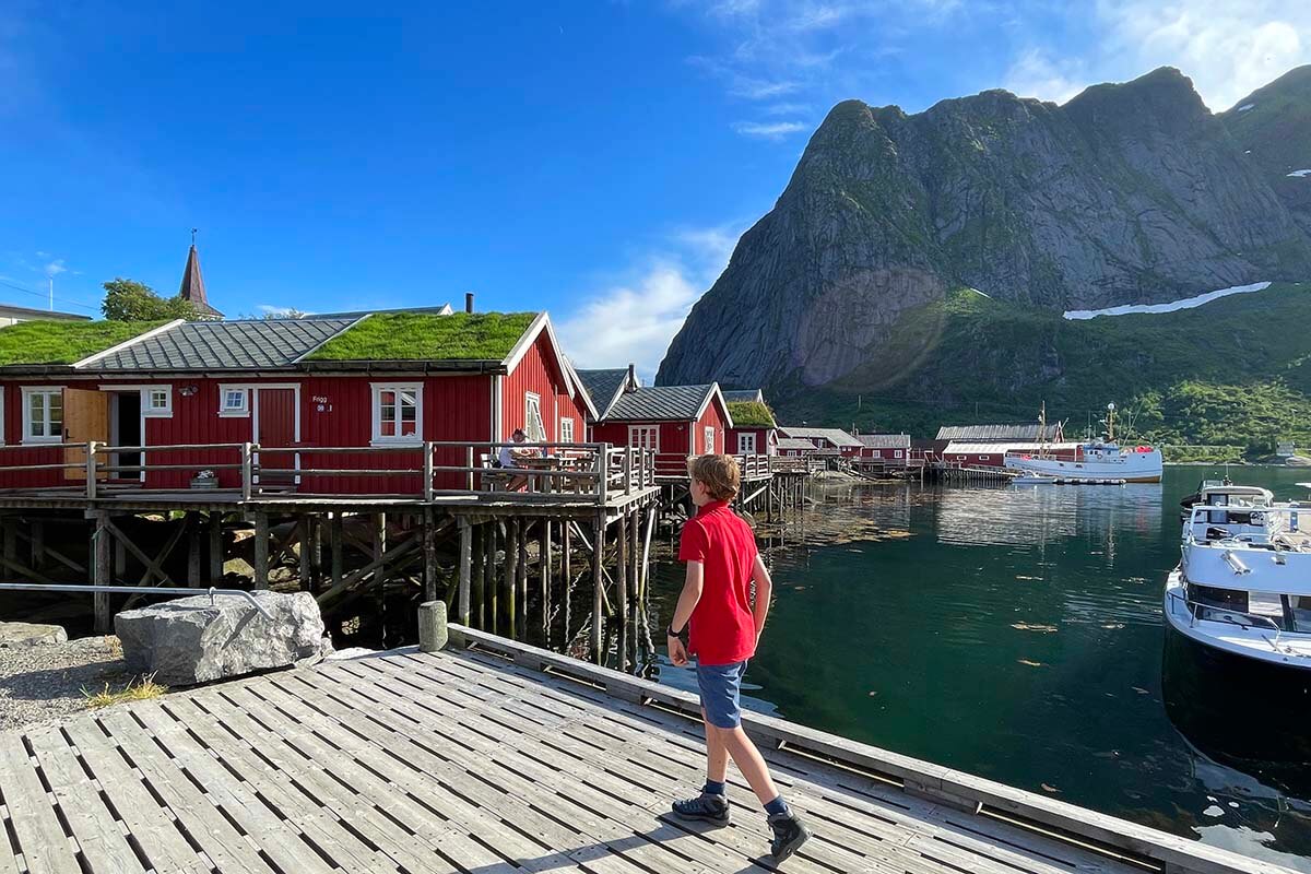 Sunny summer day in Reine, Lofoten Islands, with a child wearing shorts and a T-shirt