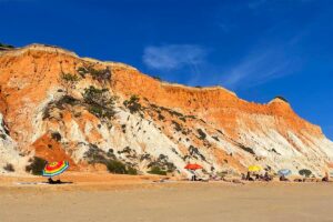 Colorful umbrellas and vacationers at Falesia Beach in Algarve in the summer