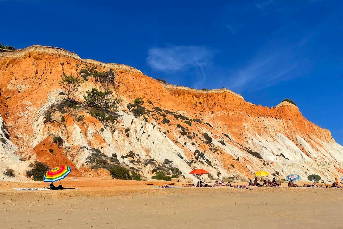 Colorful umbrellas and vacationers at Falesia Beach in Algarve in the summer