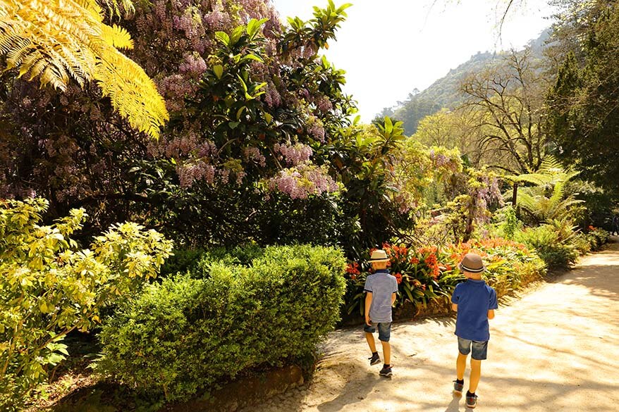 Children walking through the lush gardens of Quinta da Regaleira in Sintra, Portugal.