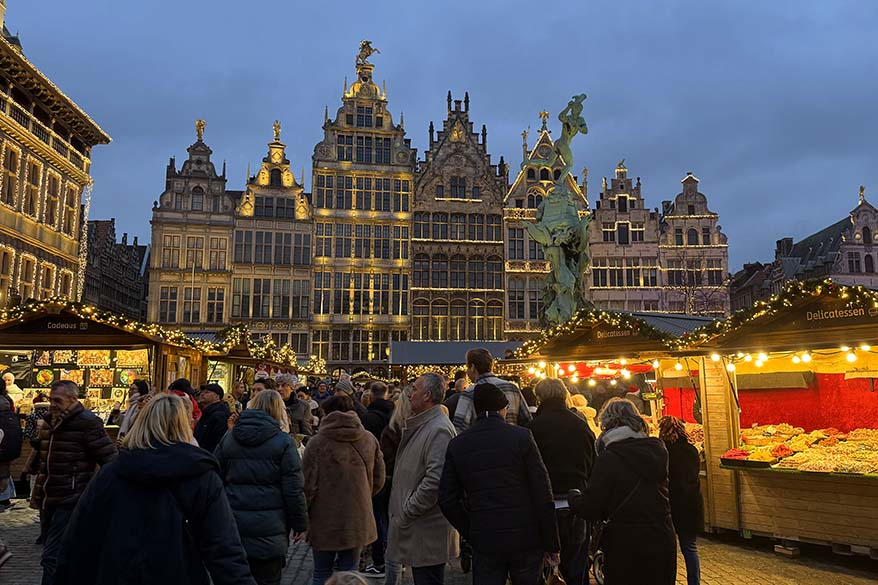 People visiting Antwerp Christmas Market on Grote Markt with historic guild houses.