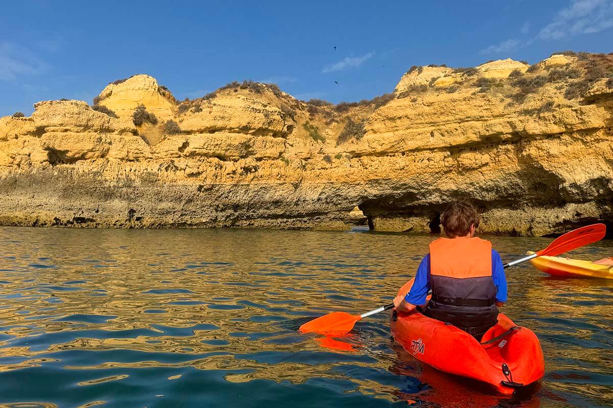 Person exploring Algarve coastline by kayak in the summer