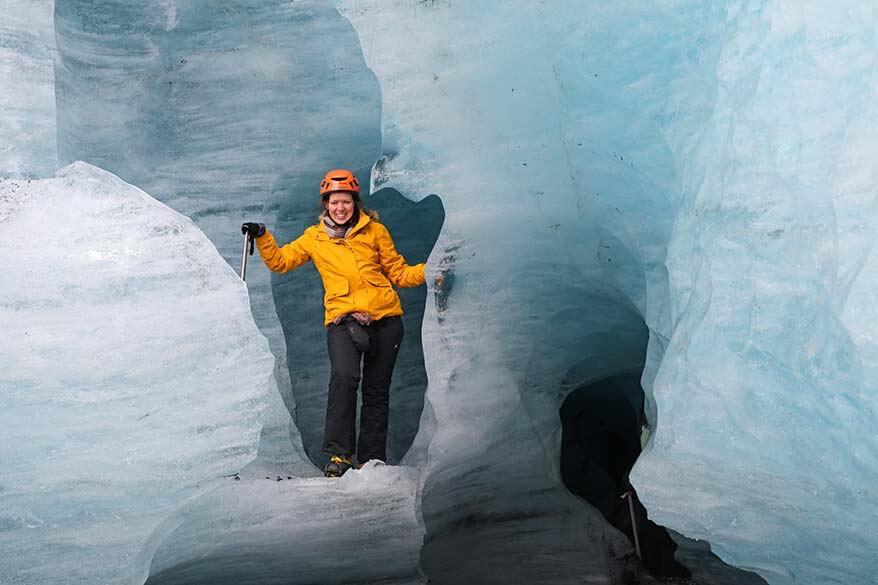 Tourist wearing warm winter clothes surrounded by glacier ice in Iceland in winter