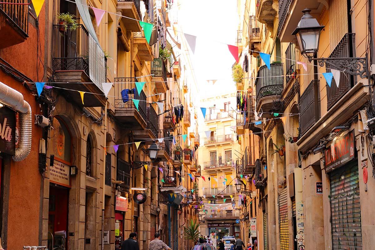 Barcelona old town street with traditional buildings and colorful flags