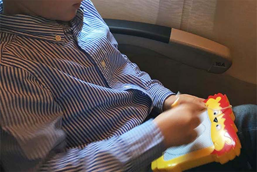 Child with a drawing pad on the plane