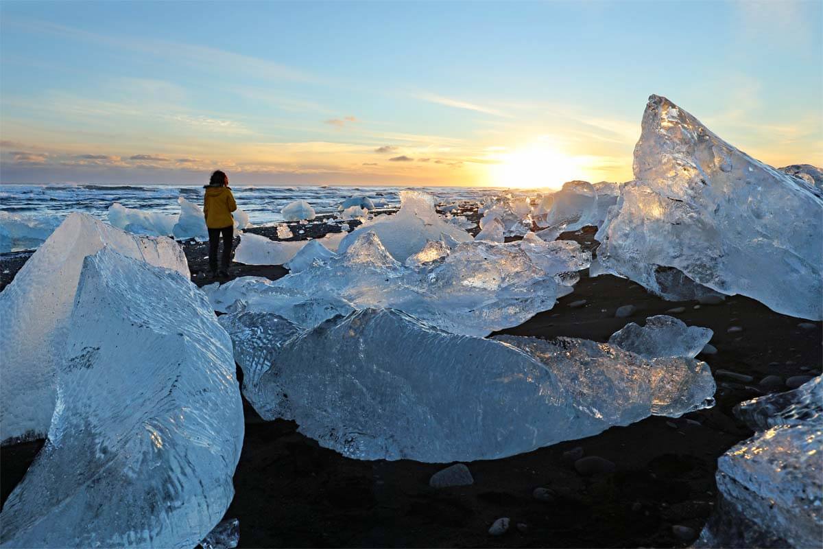 Woman walking between huge ice chunks on Diamond Beach in Iceland in winter